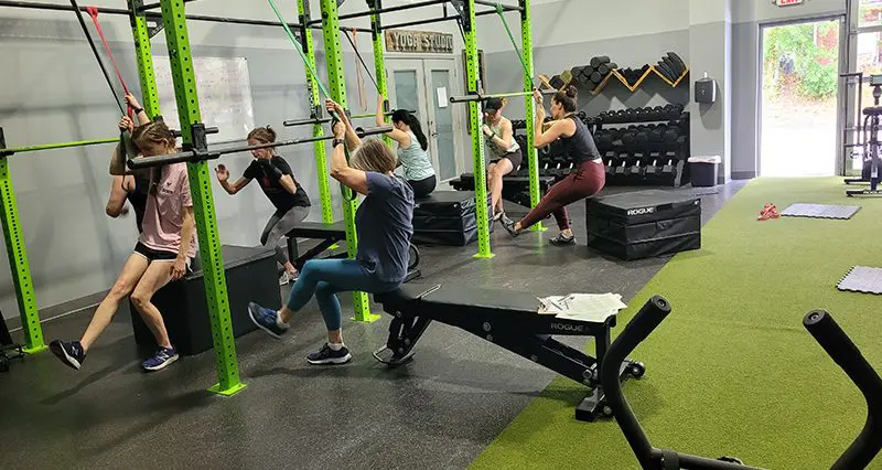 People exercising in a gym using resistance bands and benches.