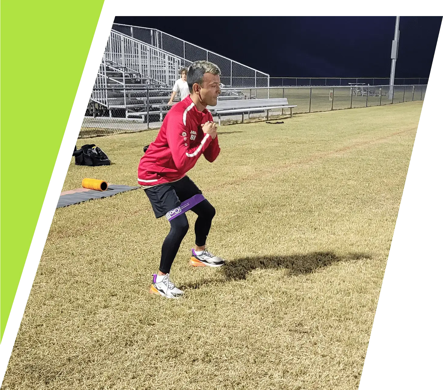 A young athlete practicing soccer on a grassy field at night.