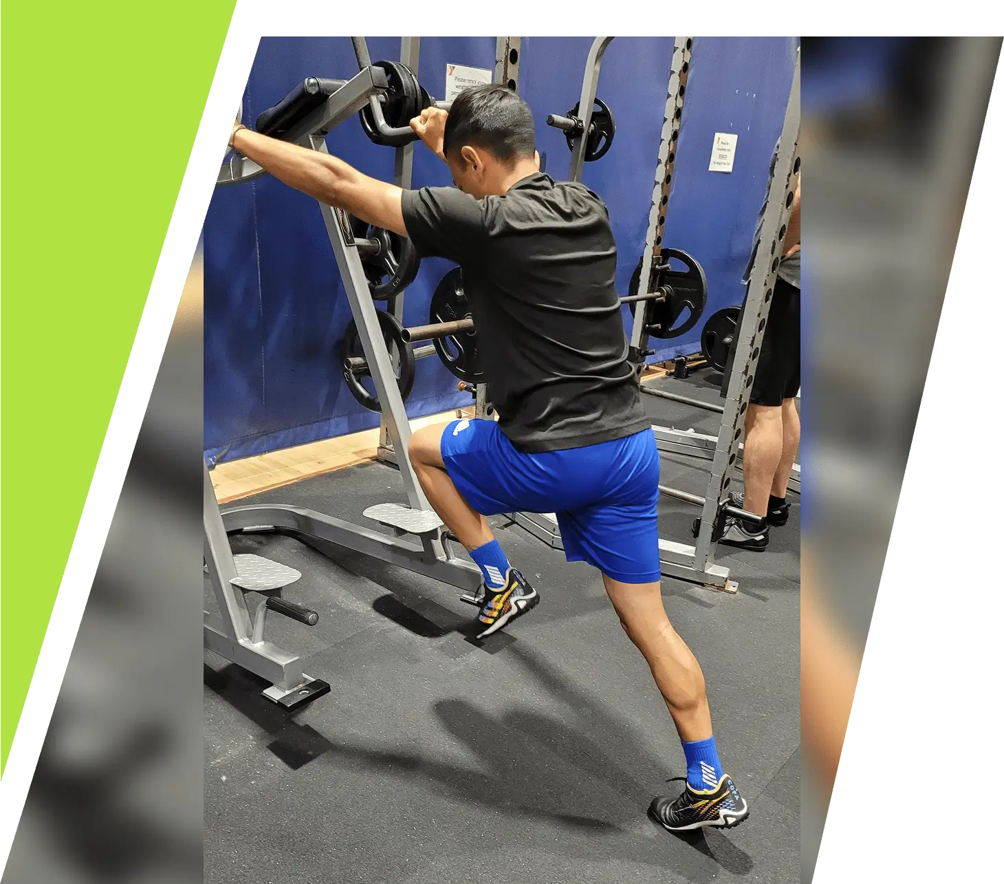 Man stretching leg on gym equipment wearing fitness gear.